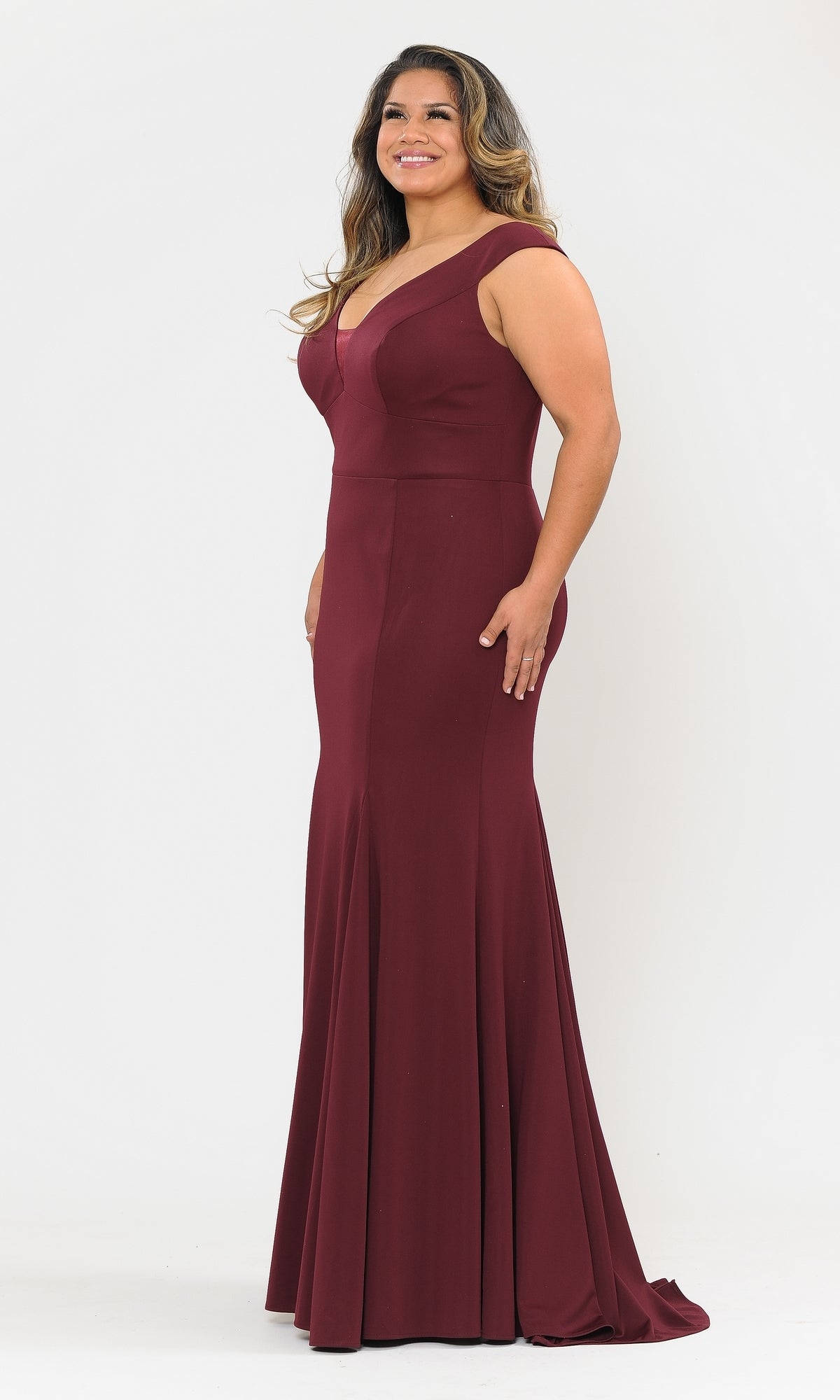 A woman in the Classic Sleeveless Plus-Size Long Prom Dress W1022, a floor-length gown with a V-neck, stands smiling and facing slightly to the side against a plain white background.